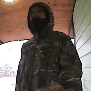 Fuzzy doorbell camera photo of suspect with camo hoodie and mask.